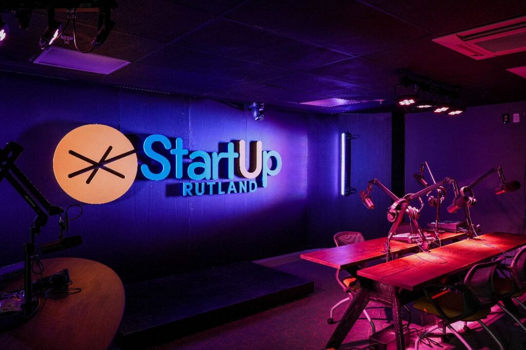 Image of the Podcast Studio with tables, microphones and headphones with a sign on the wall saying StartUp Rutland.