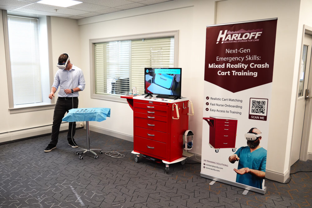 A man in business casual clothes showing off their startup's virtual reality medical cart training program at The Hub CoWorks in downtown Rutland, Vermont.