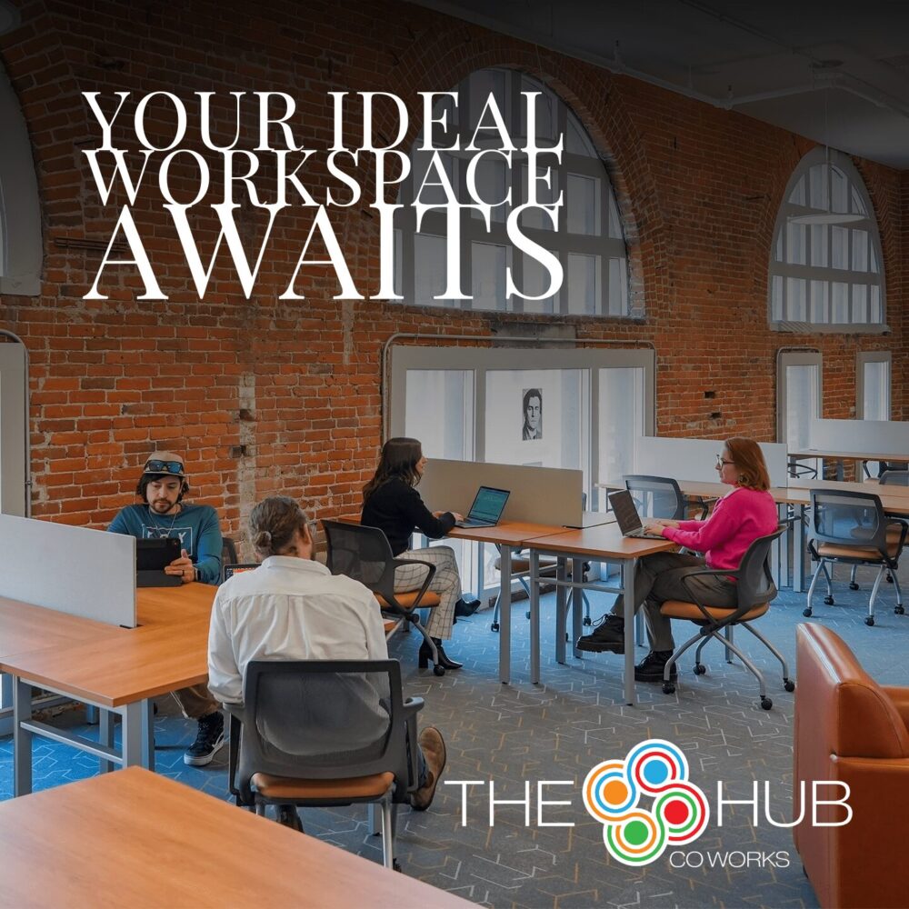 A modern coworking space with exposed brick walls and large arched windows at The Hub CoWorks in downtown Rutland, Vermont. Professionals are working at spacious desks with laptops, showcasing a productive and collaborative workspace. The image highlights the bright, welcoming environment with ergonomic chairs and natural light, inviting remote workers, freelancers, and entrepreneurs to find their ideal workspace. Text overlay reads: ‘Your Ideal Workspace Awaits’ with The Hub CoWorks logo at the bottom.