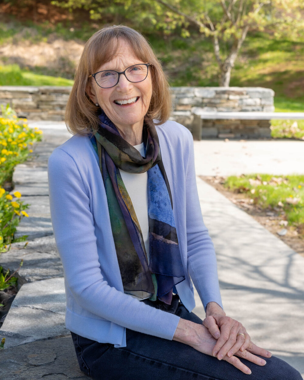 A portrait photograph of Community College of Vermont's President, Joyce Judy. She is wearing a lilac cardigan with a multi-colored scarf.
